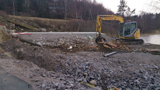 Gravemaskin og rester av bygg